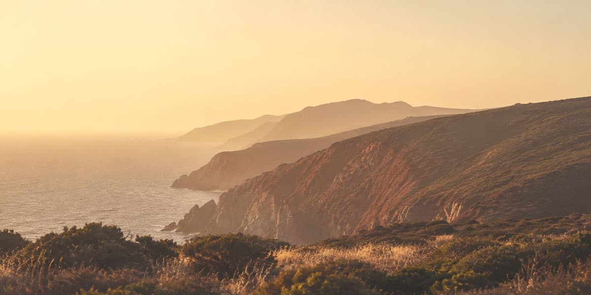 Layered coastal headlands receding into golden-hour haze